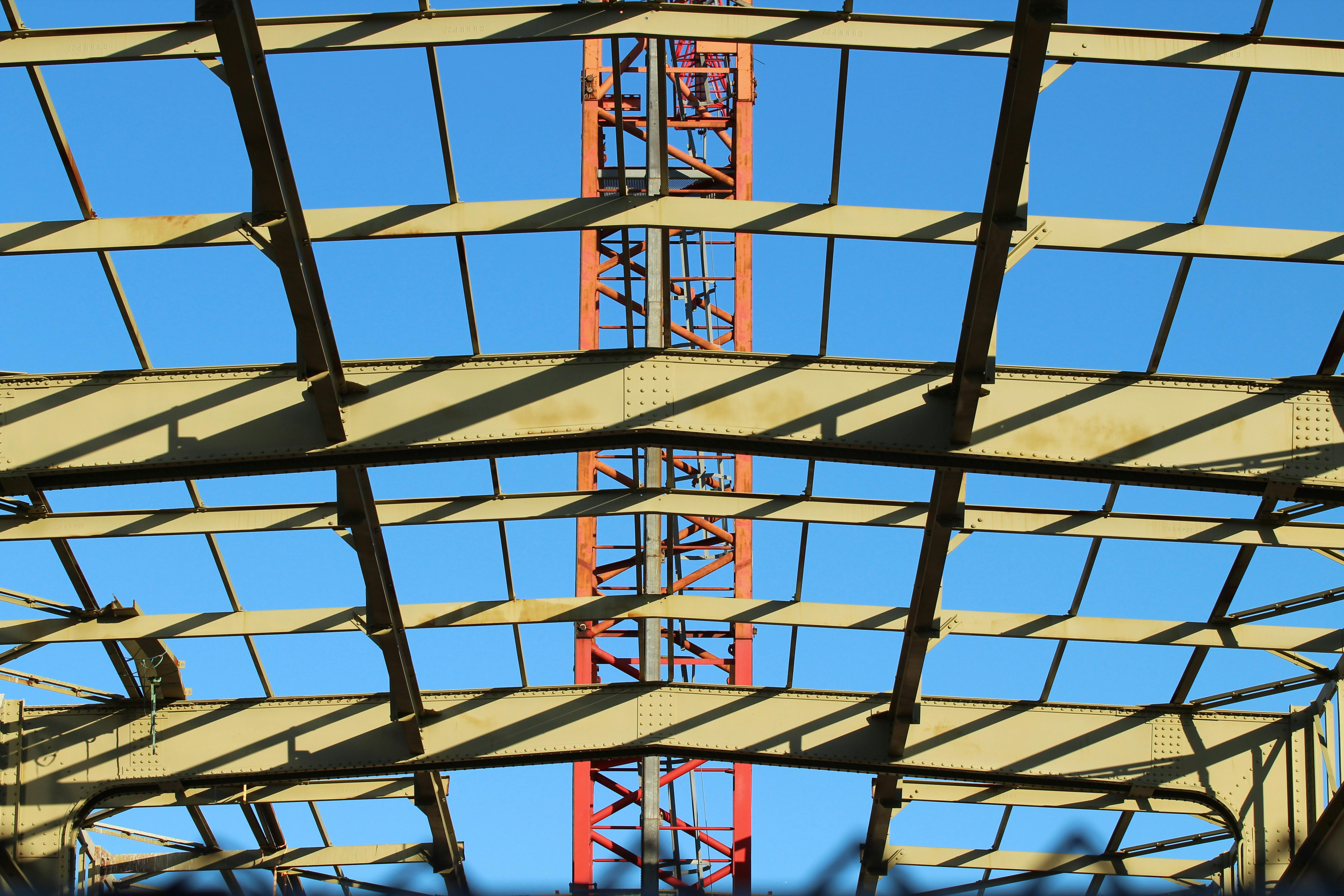 Industrial steel frame structure with girders and beams under a clear blue sky, shown as an alternative to a post tension slab.